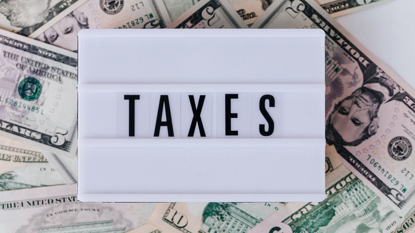 Lightbox sign reading TAXES on top of U.S. dollar bills