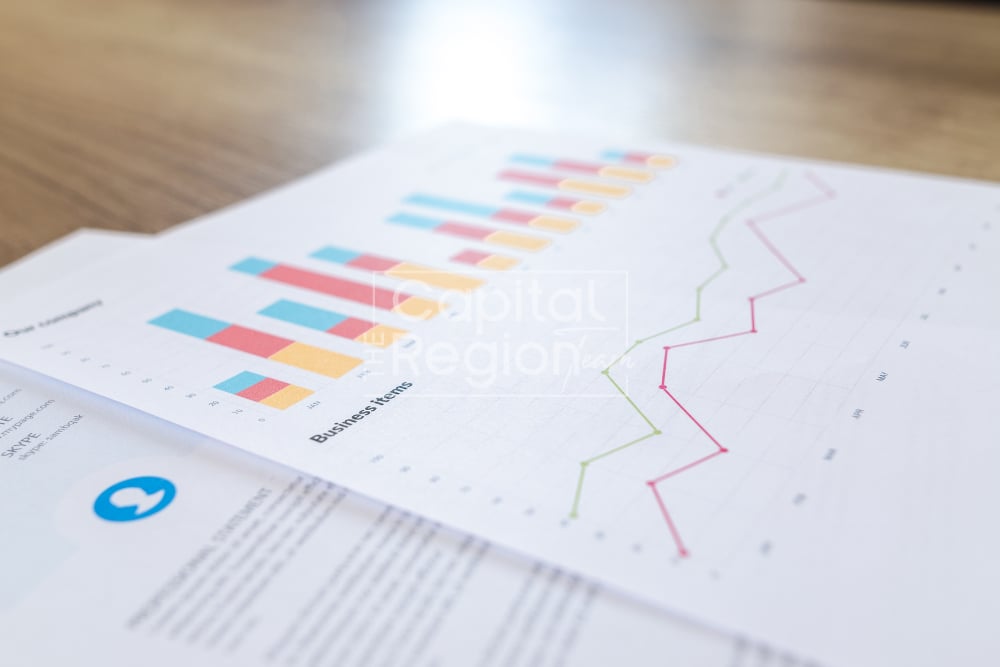 Printed business charts with colorful bars and pink and green line graphs.