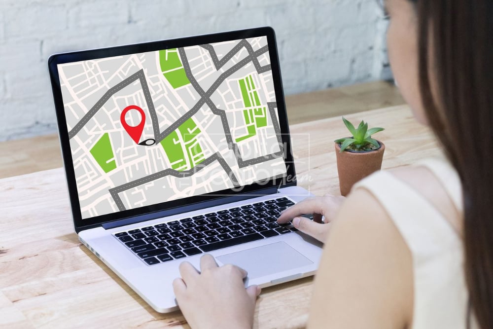 Person using a laptop displaying a city map with a red location pin.