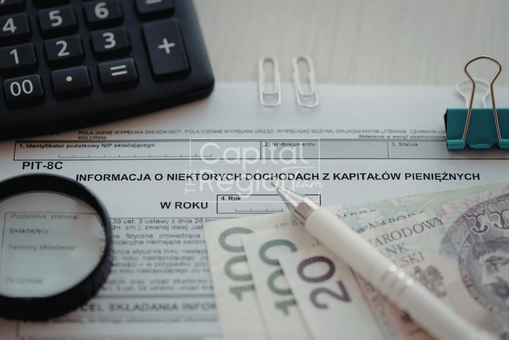 PIT-8C tax form with banknotes, calculator, magnifying glass, and pen.