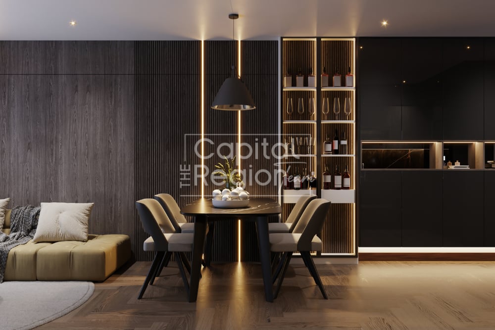 Modern dining area with a round table, upholstered chairs, illuminated shelving, and adjoining living space.