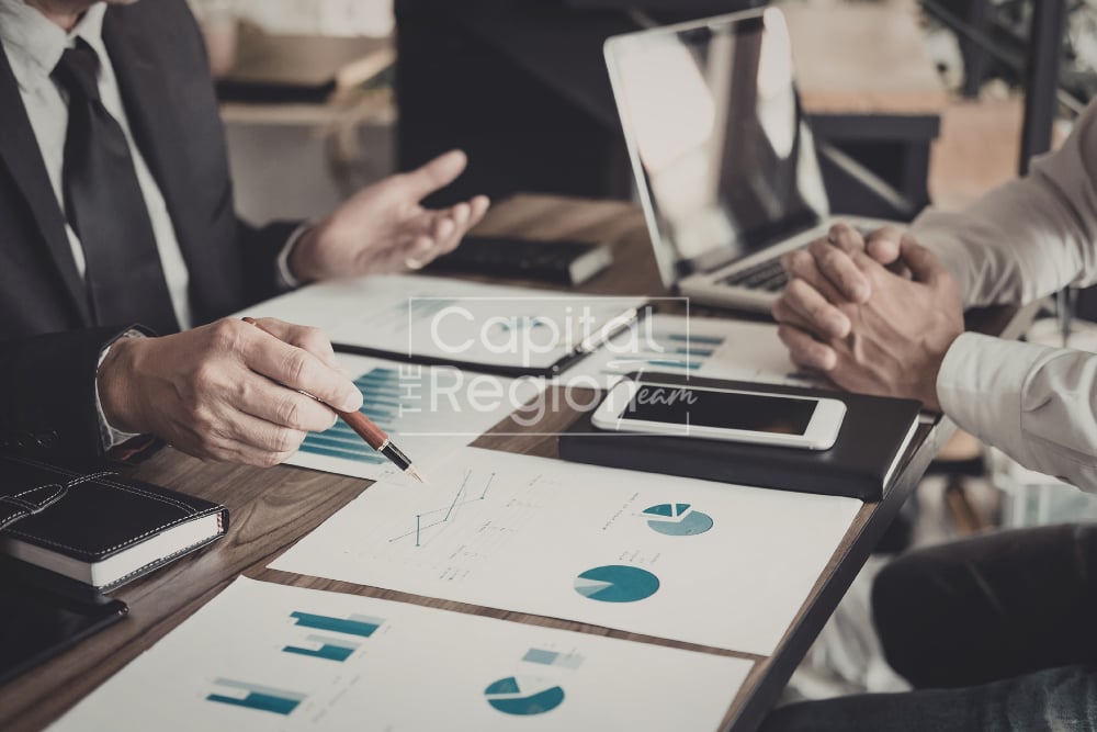 Colleagues review charts and graphs around a conference table.