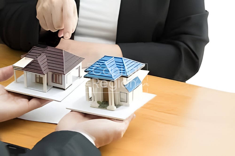 People compare two miniature homes, one with a dark roof and one with a blue roof.