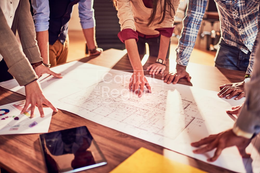 People review architectural plans around a table.