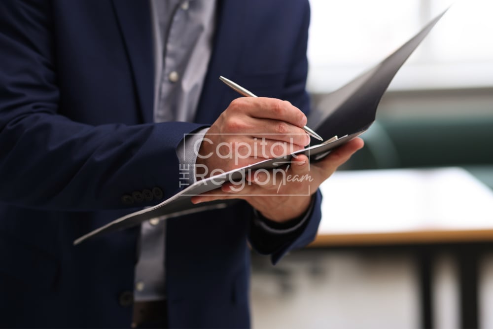 Professional in a navy suit writing on a tablet with a stylus.