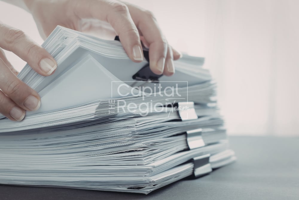 Hands sort through thick stacks of clipped paperwork.