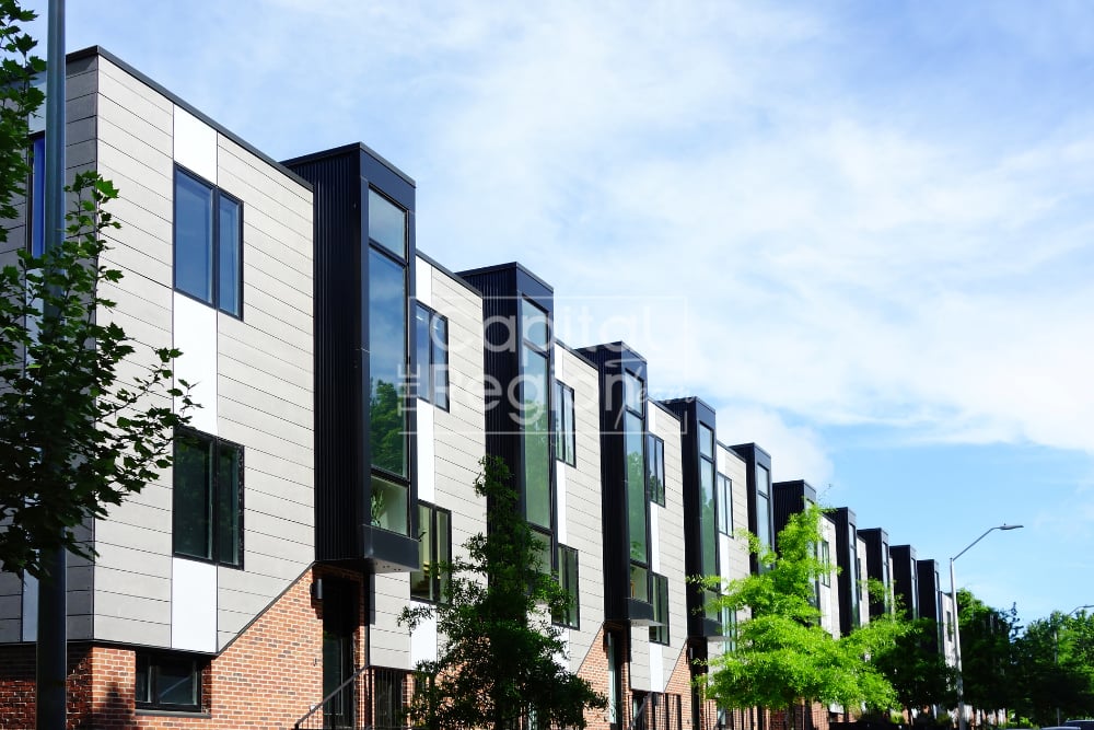 Modern attached townhouses with white siding, black accents, and brick lower facades.
