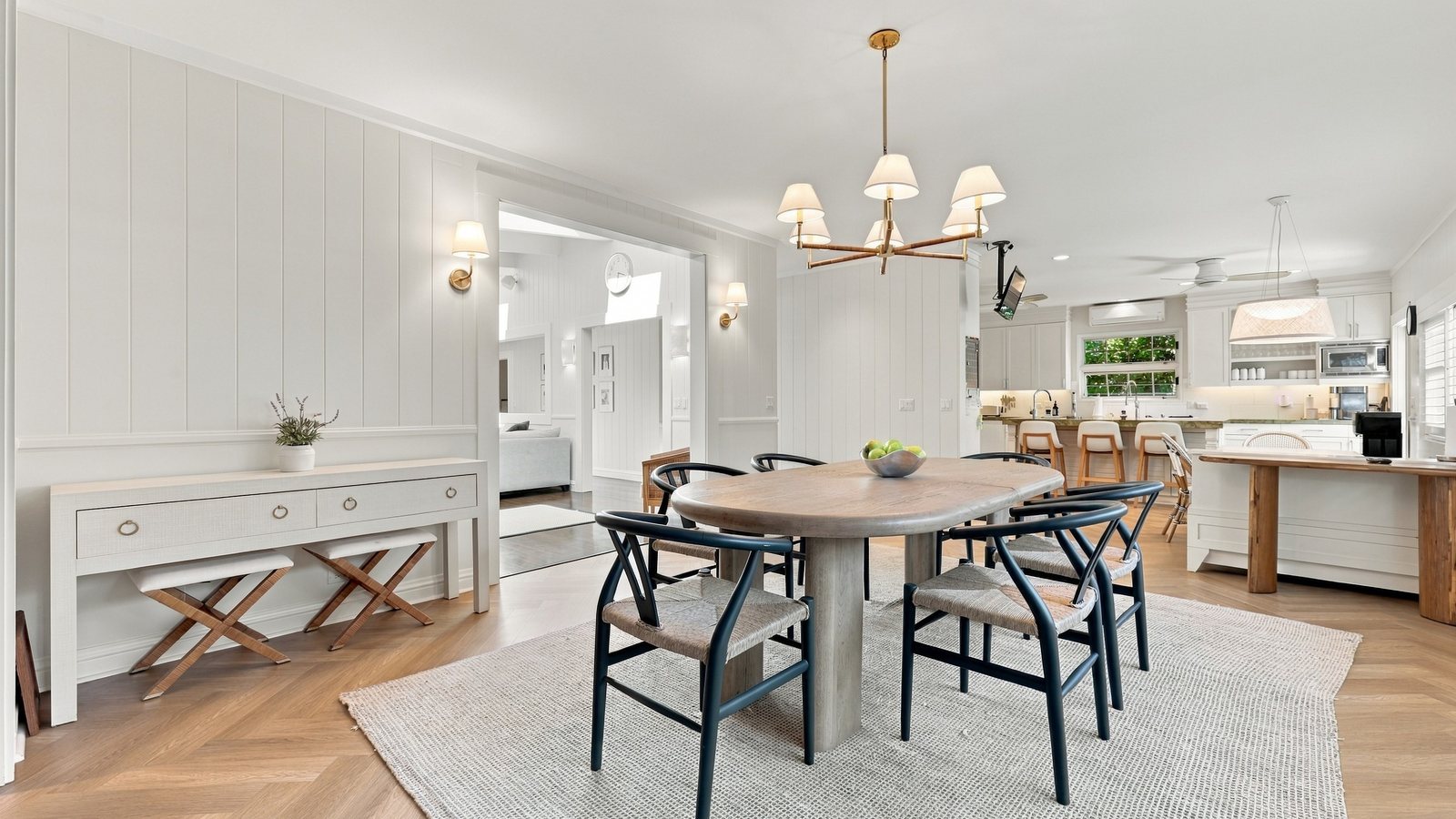 Bright dining room with a round table, pendant chandelier and open kitchen beyond