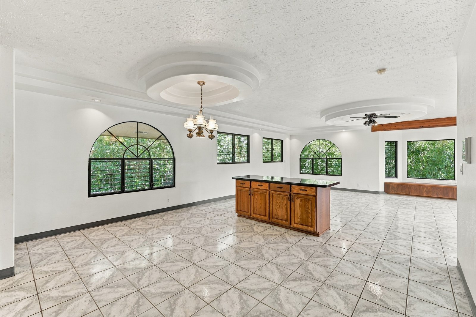 Empty open living and dining area with tile floors and arched windows