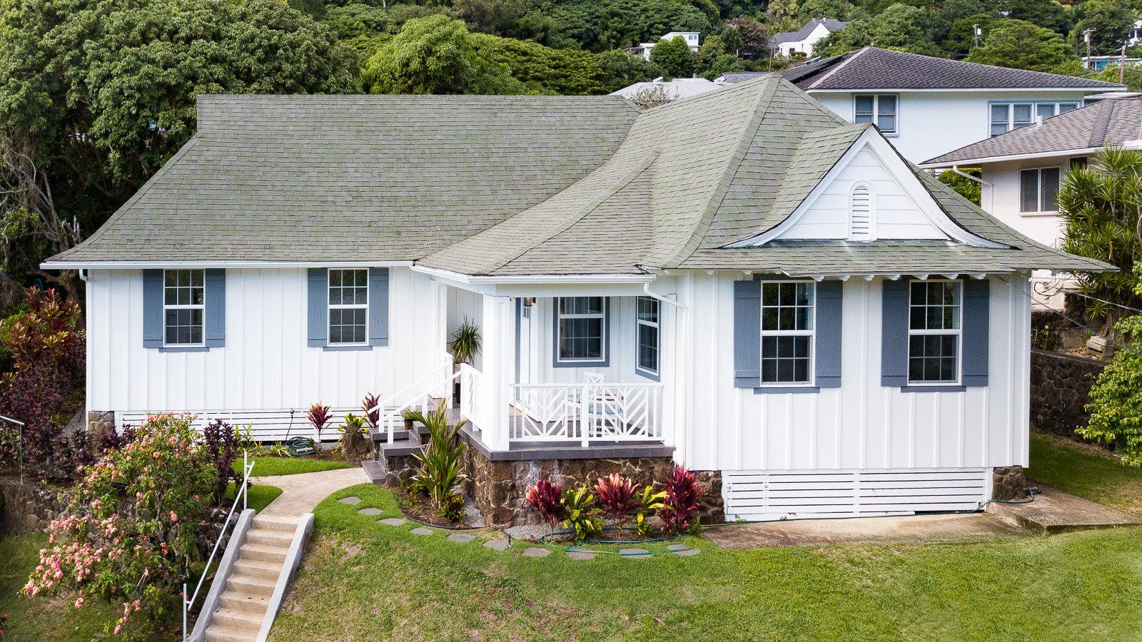 White plantation-style single-family home with green shutters on a landscaped Honolulu lot