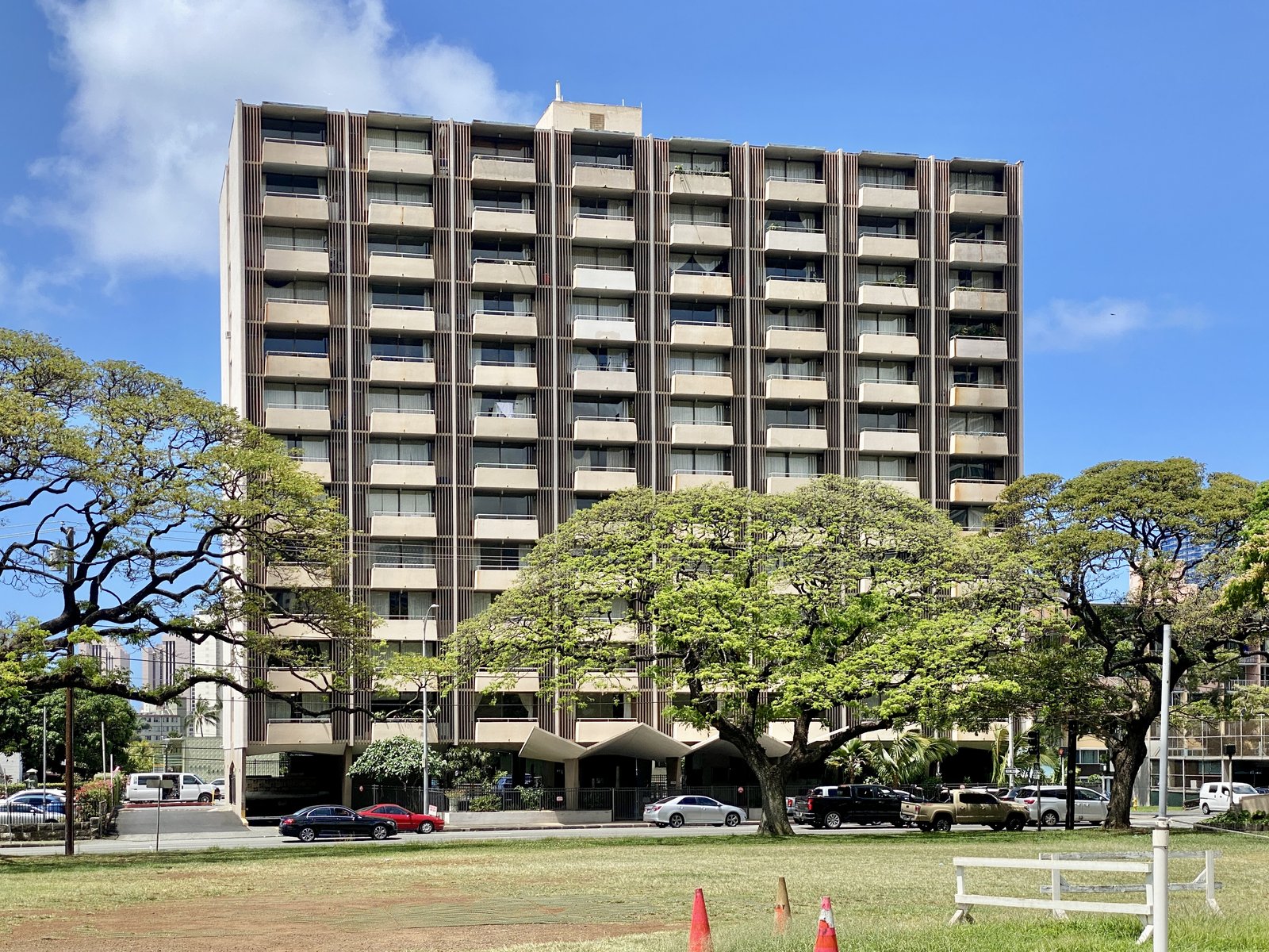 Older mid-century apartment high-rise in Honolulu behind monkeypod trees