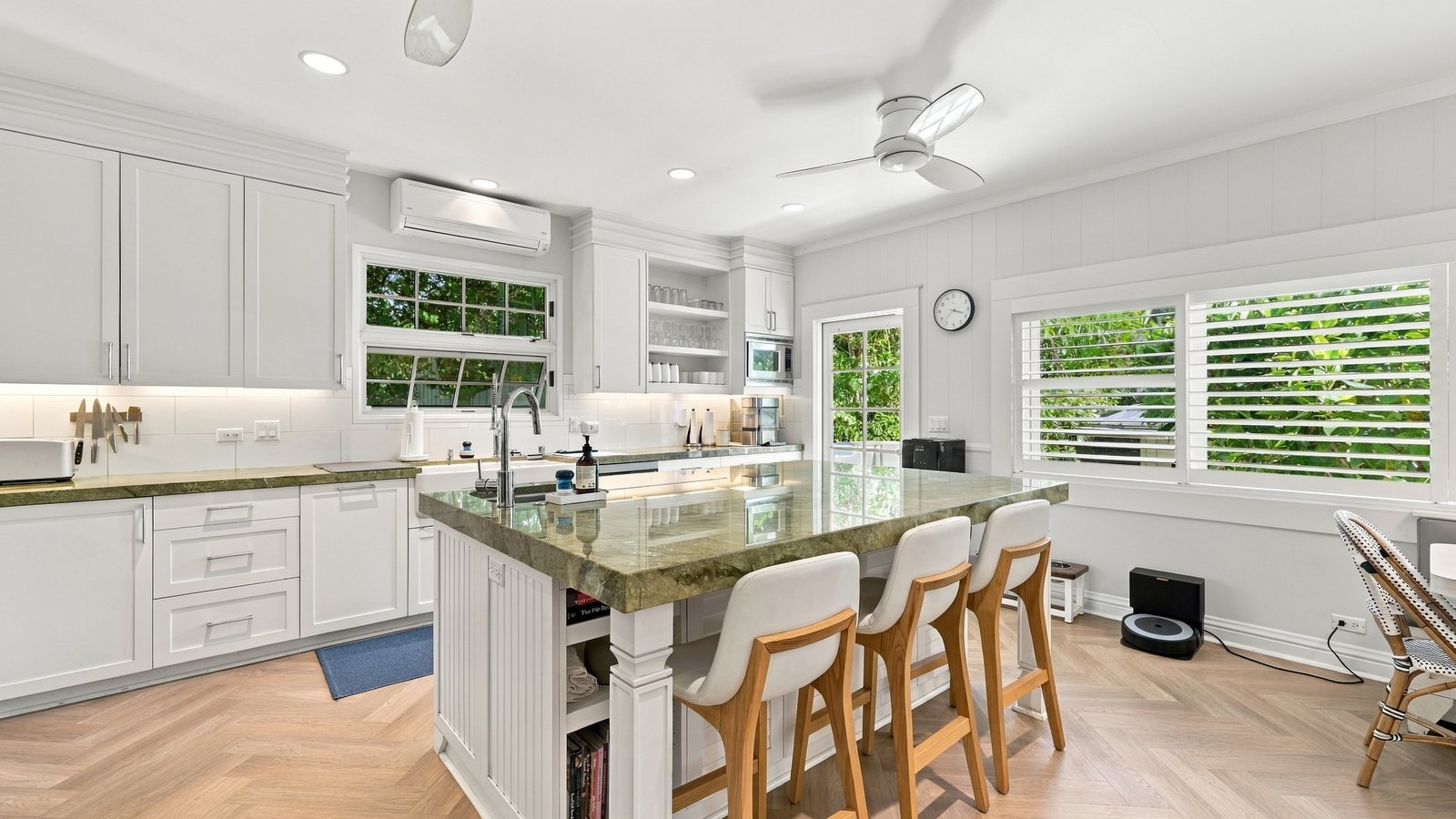 Remodeled kitchen with a marble island, bar stools and white cabinetry