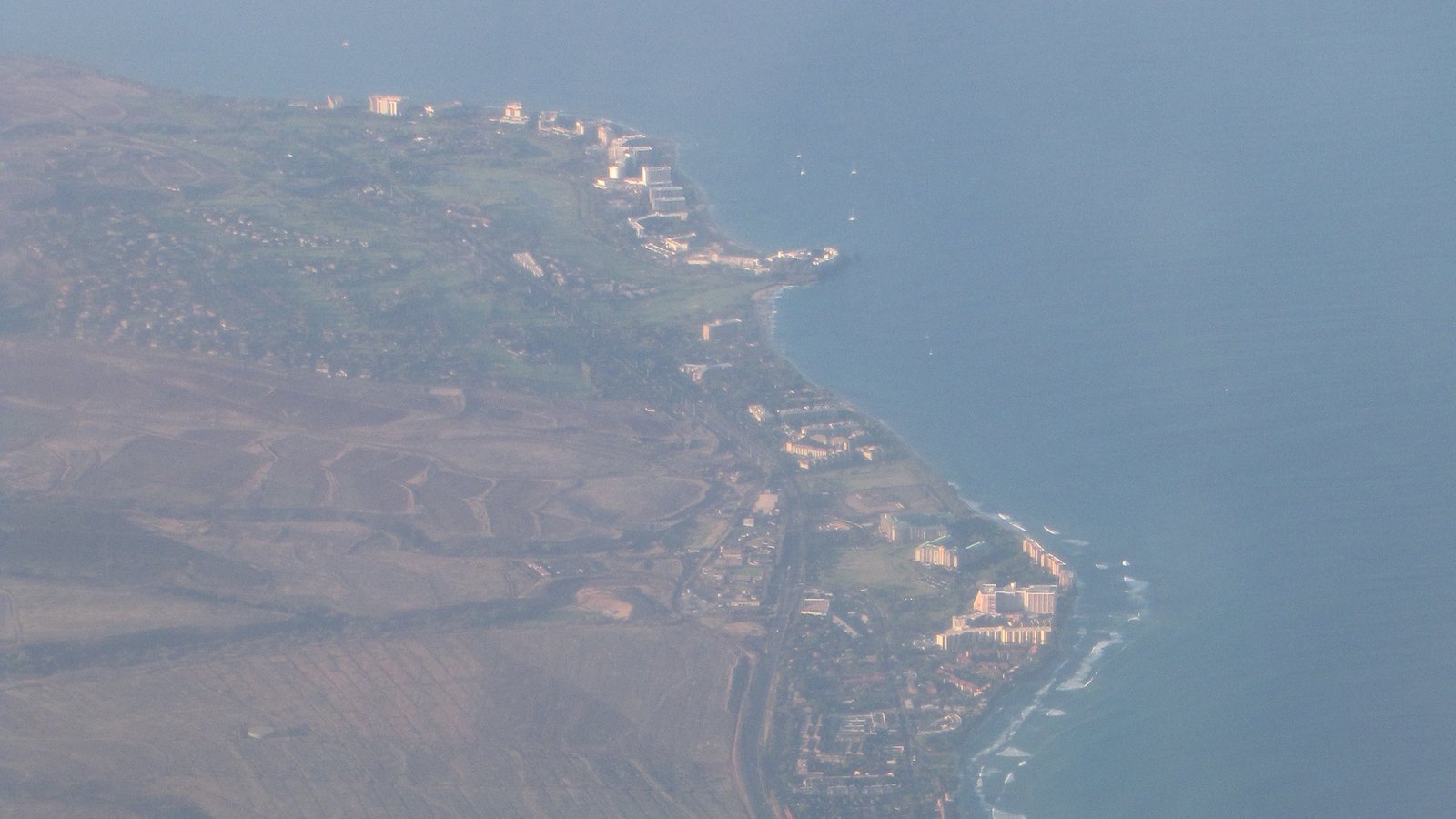 Aerial view of the West Maui coastline with resort and condo buildings along the shore