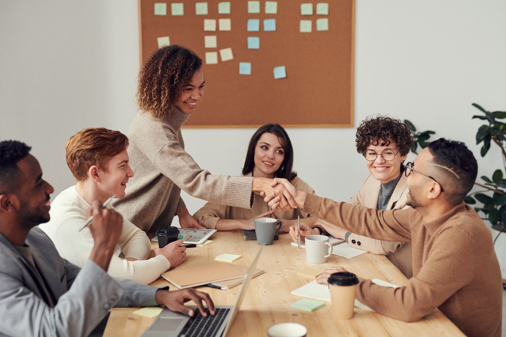 A group of people sitting around a table looking at a computerDescription automatically generated with medium confidence