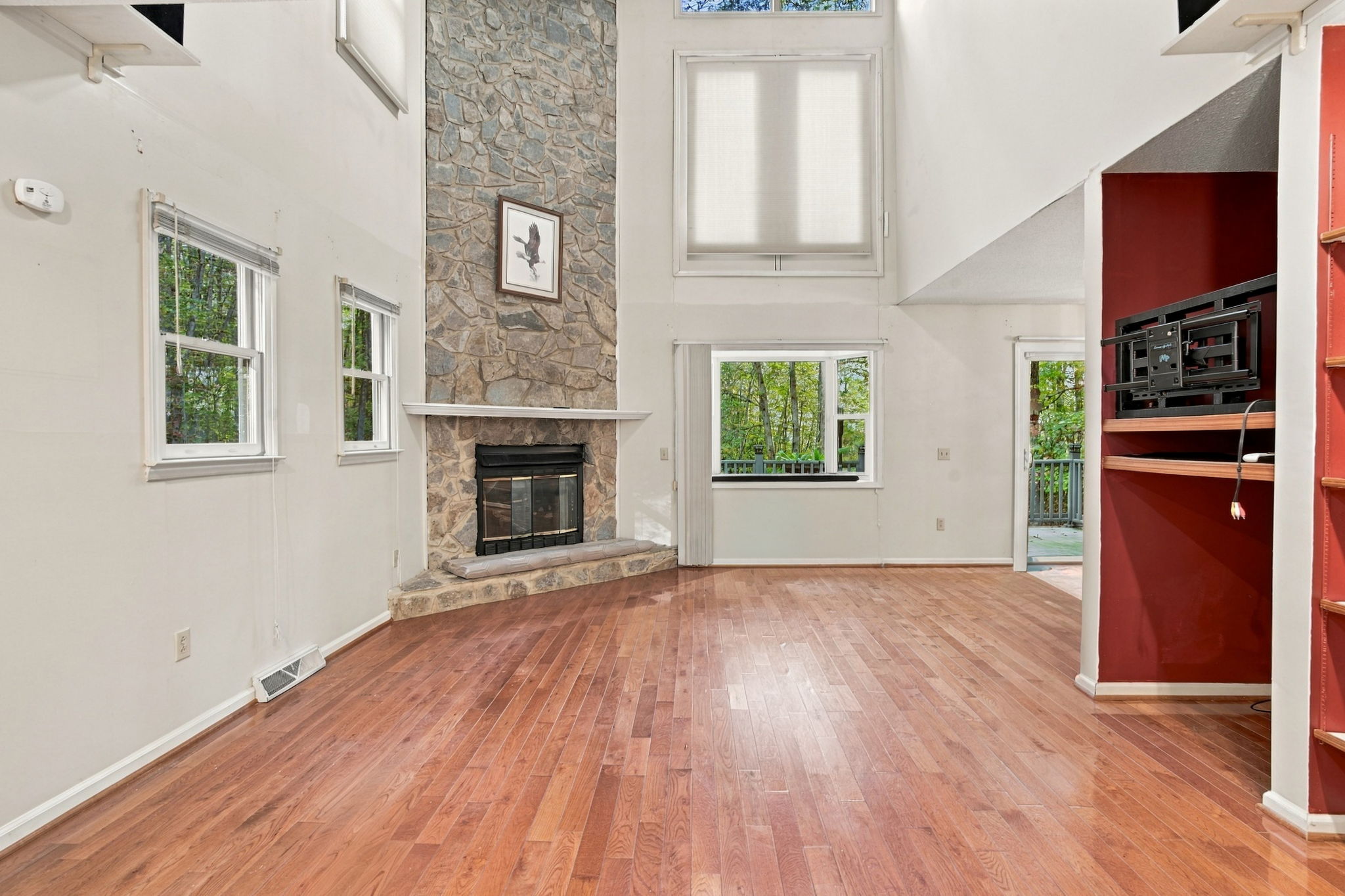 Actual unfurnished great room with vaulted ceiling, stone fireplace and hardwood floors