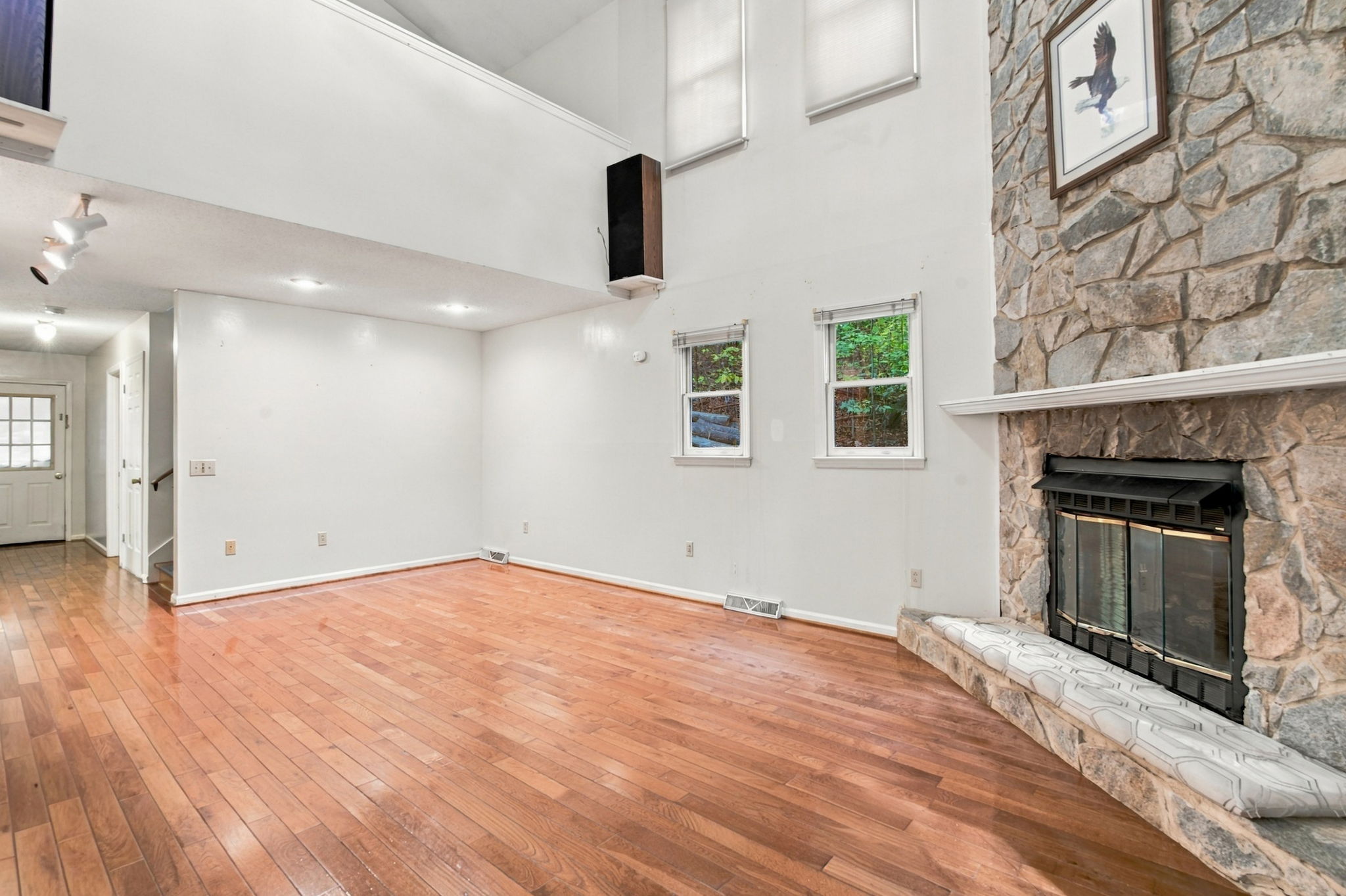 Unstaged angle of stone fireplace and open great room