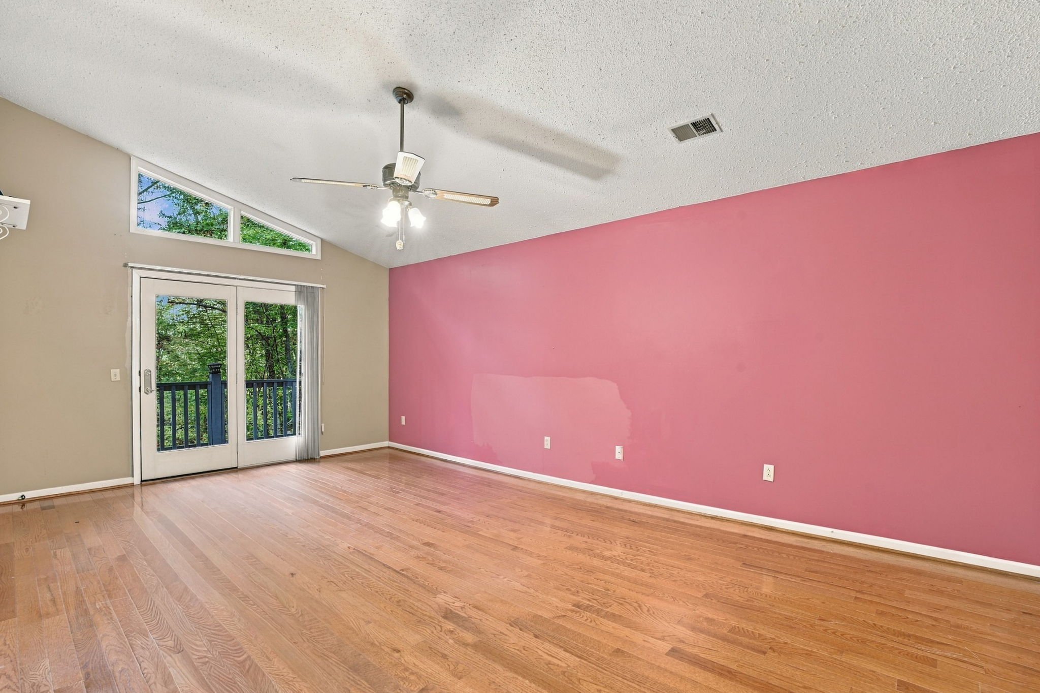 Actual upper-level primary bedroom with painted accent wall and deck doors
