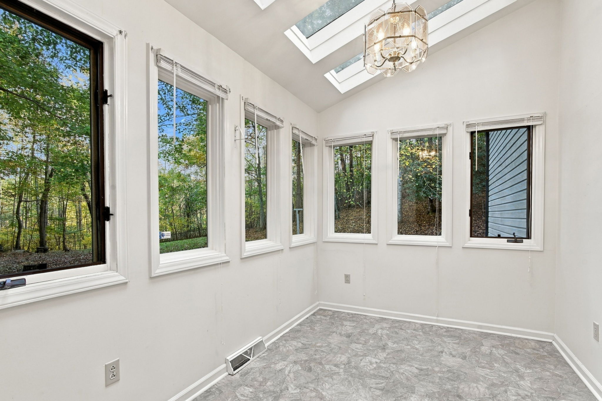 Original photograph of bright unfurnished sunroom with multiple windows