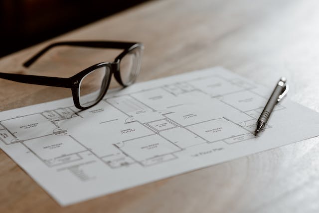 Pair of glasses on a piece of paper with apartment blueprints on it.