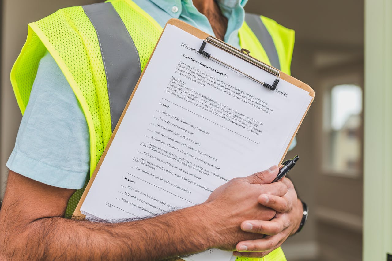  A man in a safety vest holding inspection notes and a pen.