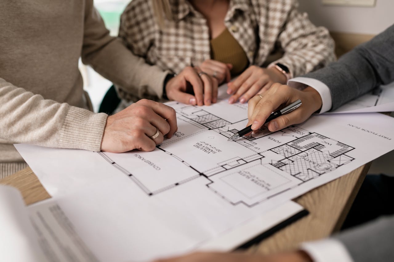  A man explaining a floor plan to a male and a female.