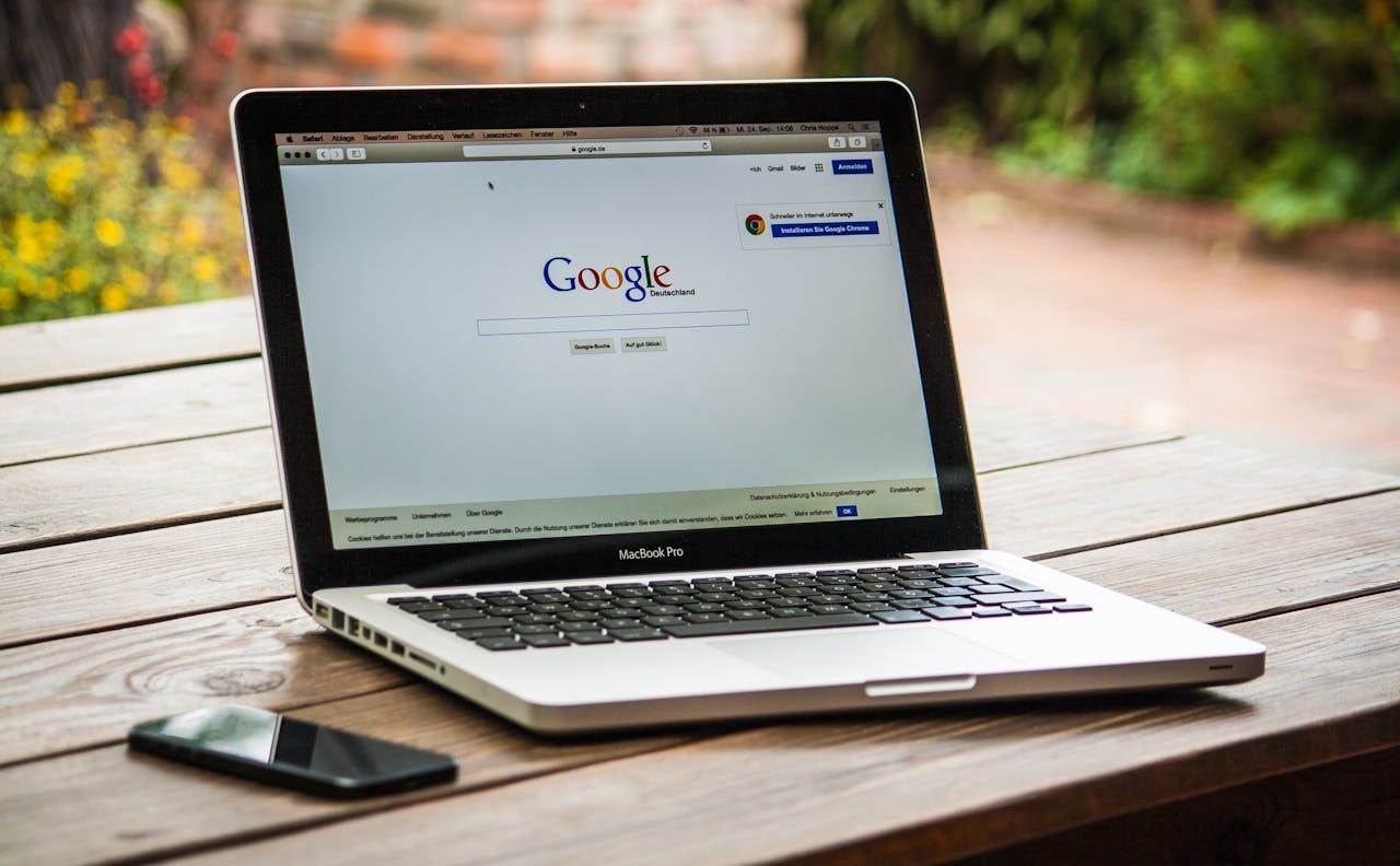 A laptop on a wooden table with Google search on its screen.