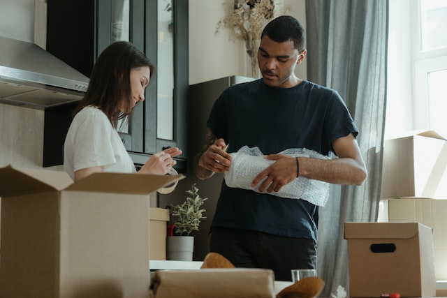 Man and woman packing items in cardboard boxes