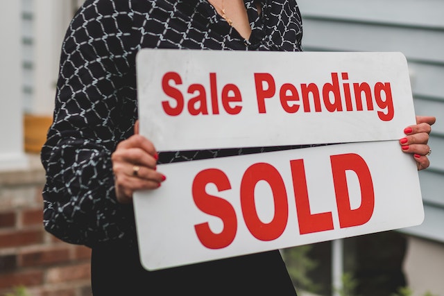 a person holding SALE PENDING and SOLD signs