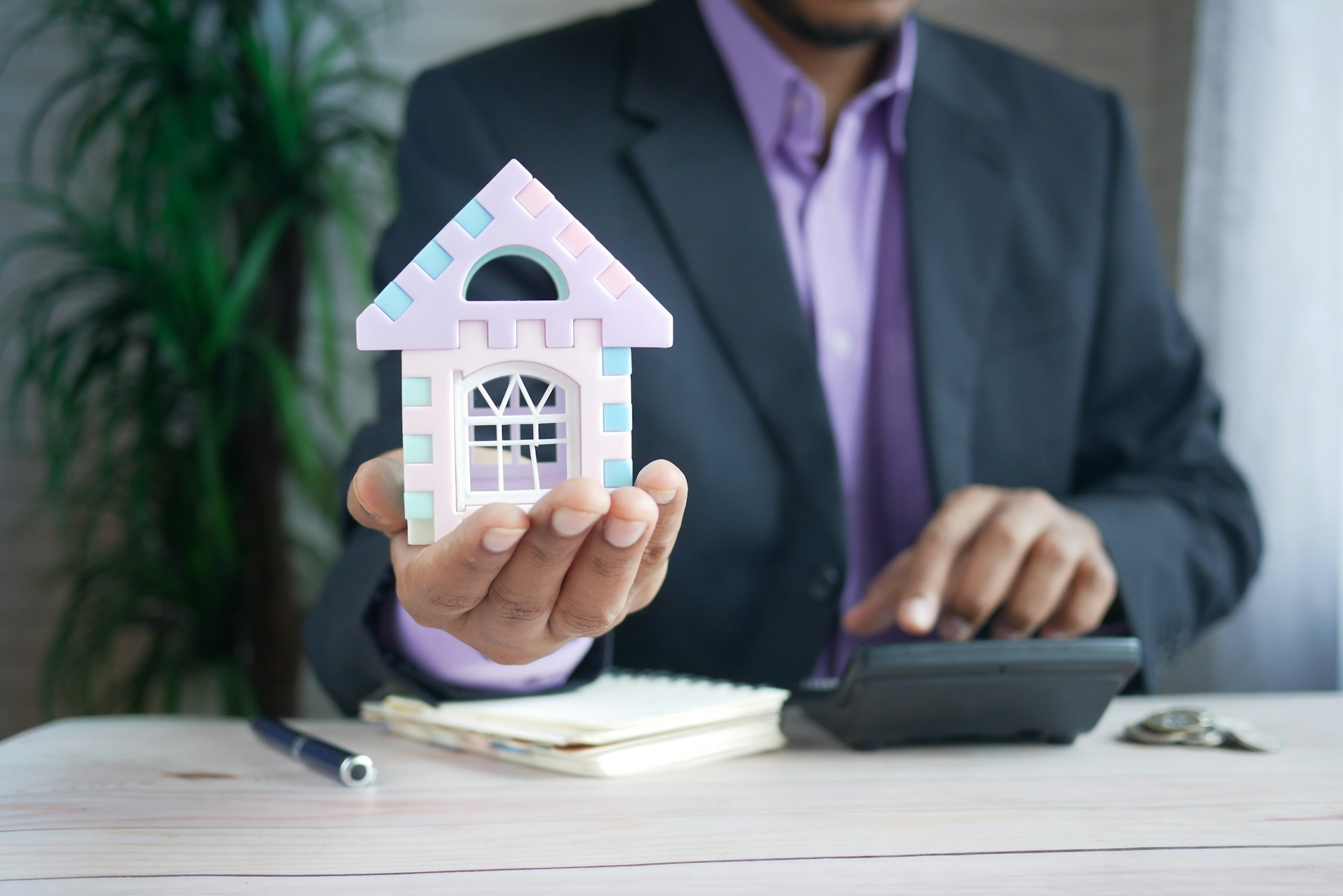 A person holding a miniature house model.