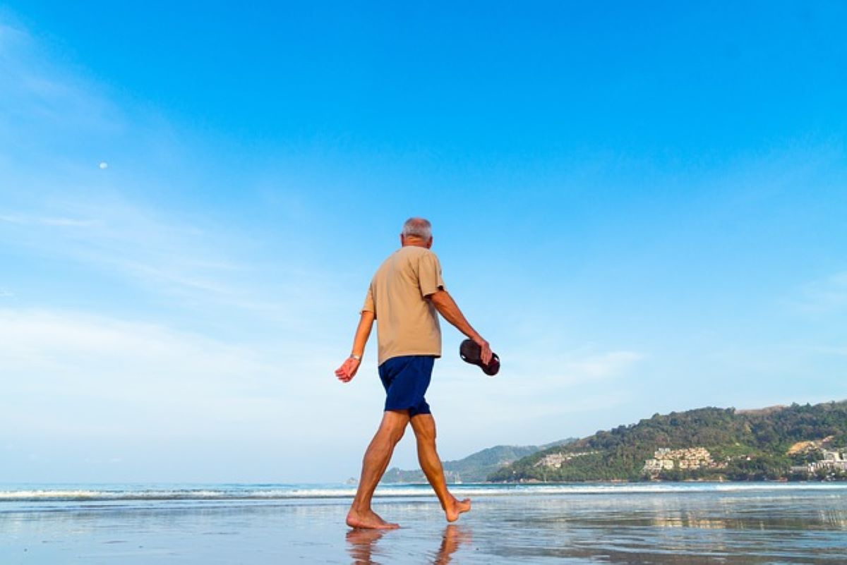 A man is walking on the beach because South Carolina is an ideal destination for snowbird retirement.