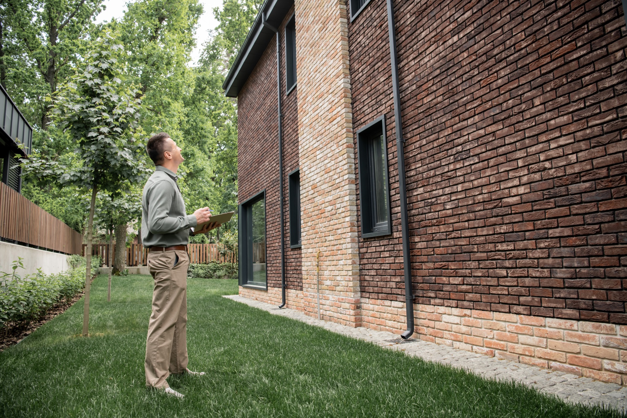 Home inspector examining the exterior of a brick house before a real estate sale