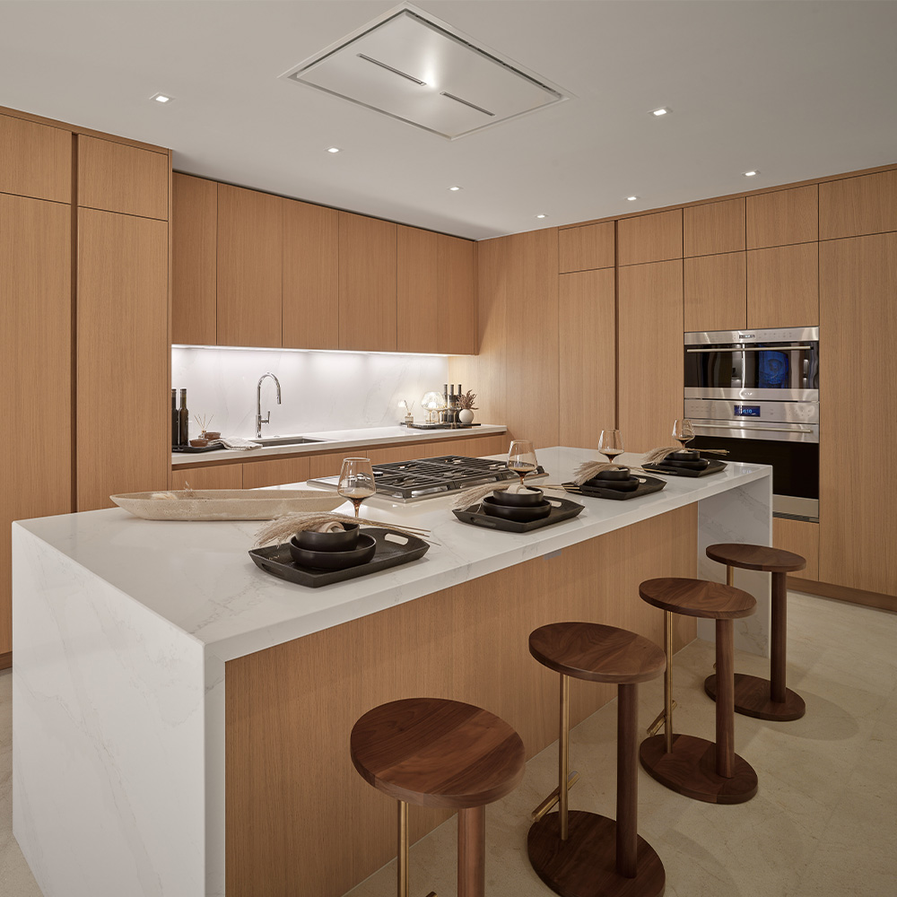Kitchen with full-height wood cabinetry and a stone island at Pier Sixty-Six Residences