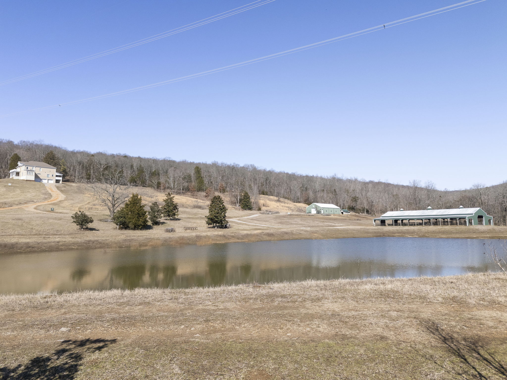 Scenic pond and creek on the property with the stable and residence in the background.