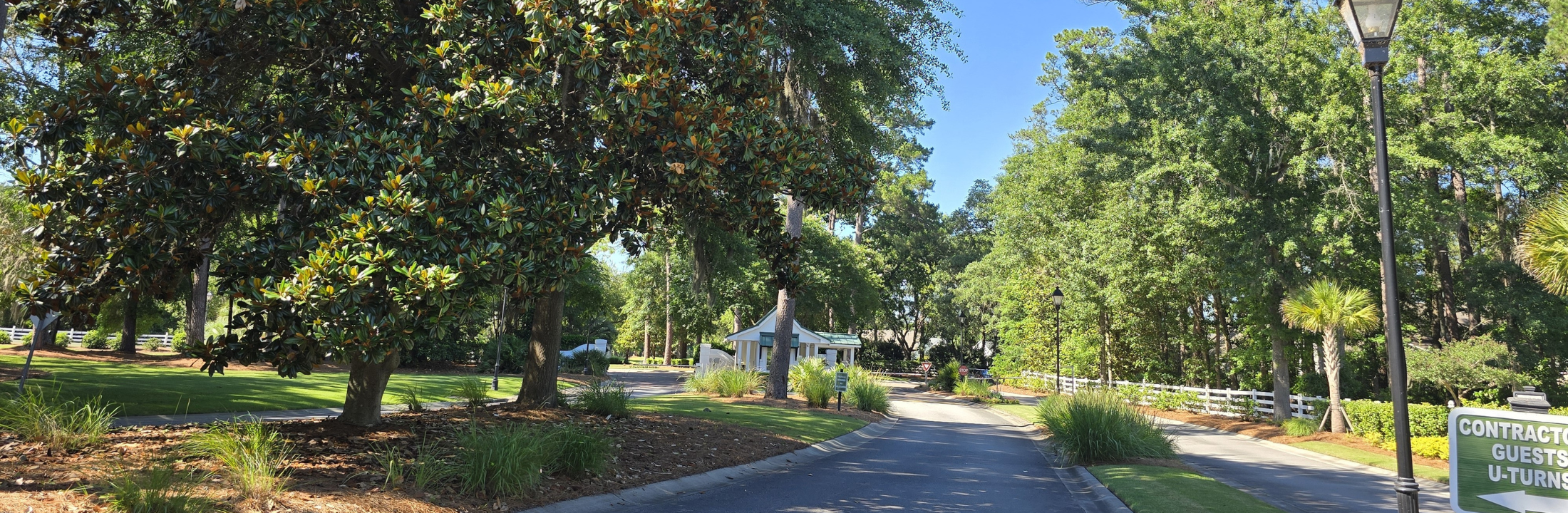 The Crescent entrance drive lined with magnolias and palmettos leading to the staffed guard house in Bluffton, SC