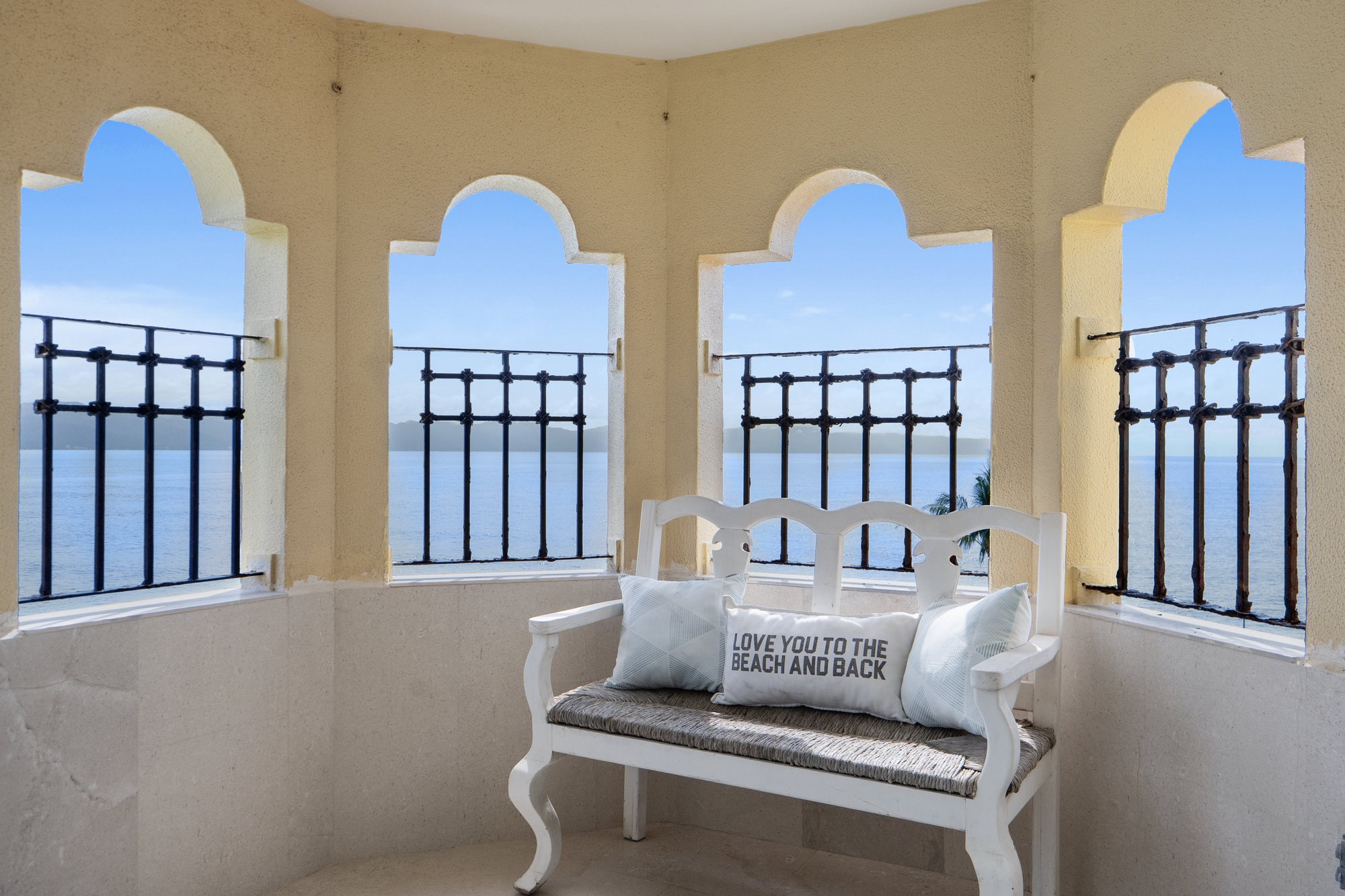 Esquina de la terraza con arcos y una banca frente al mar