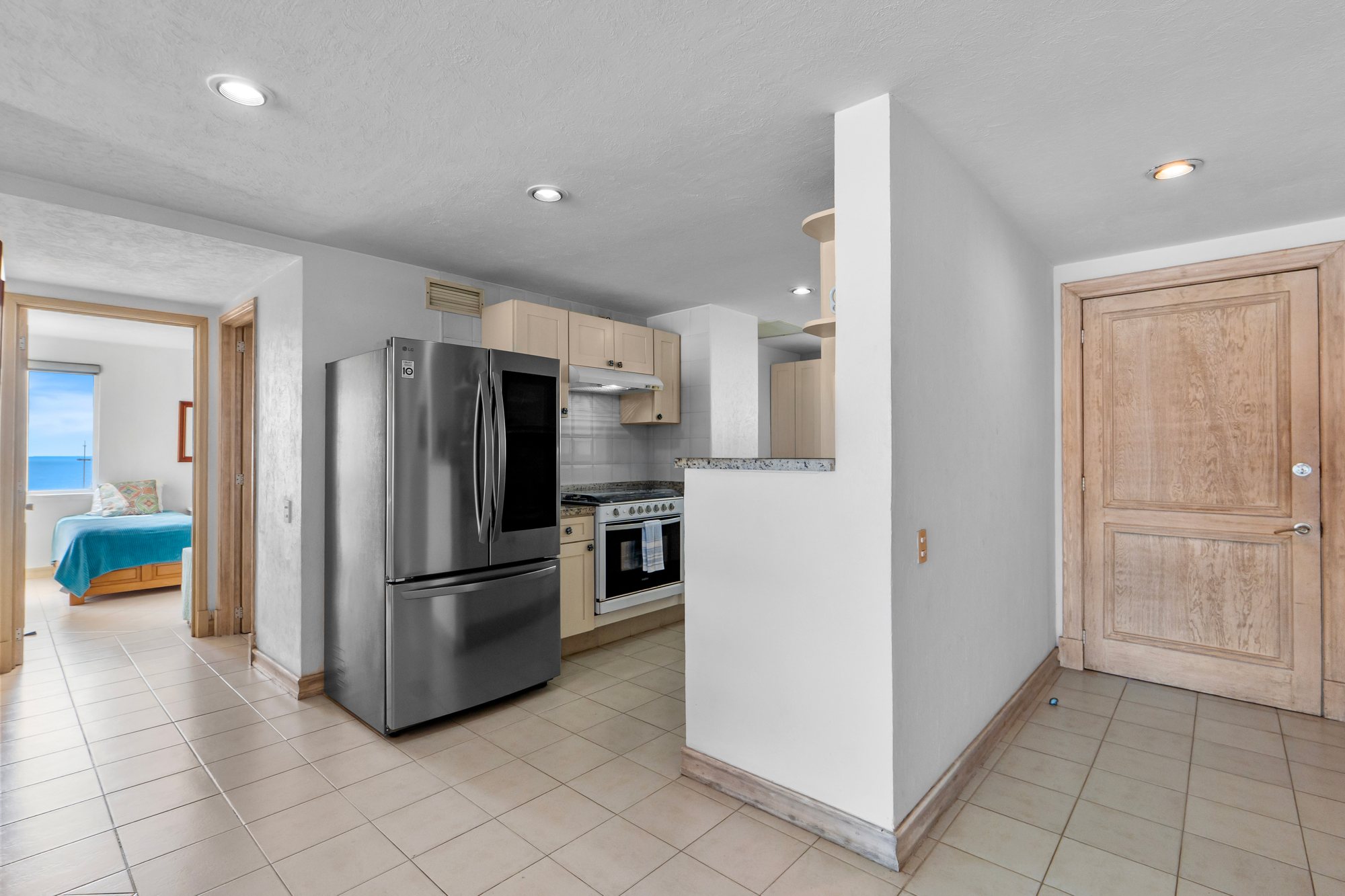 Cocina con refrigerador de acero inoxidable junto a la entrada