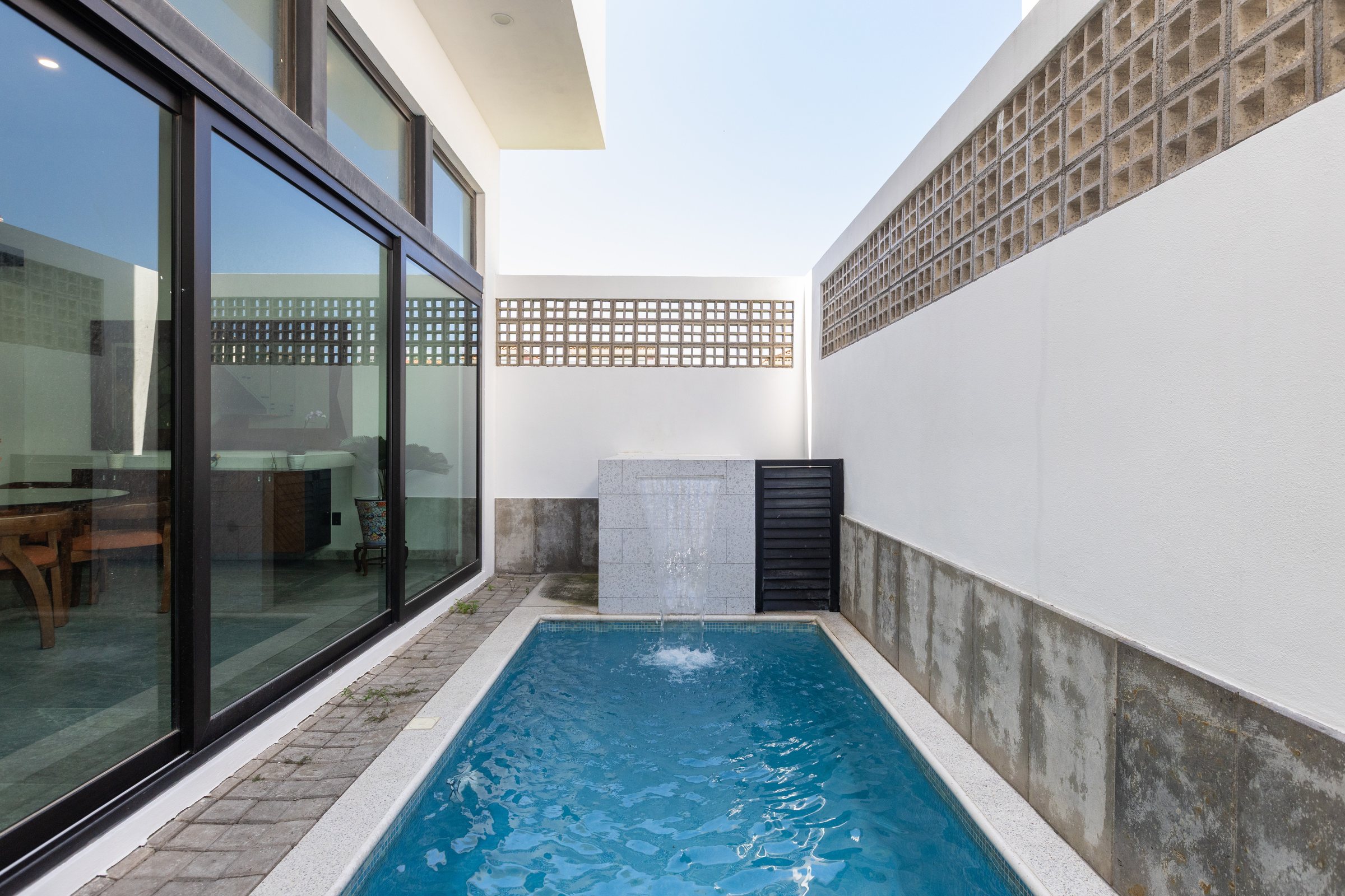 Private pool with a waterfall beside the glass-walled ground floor