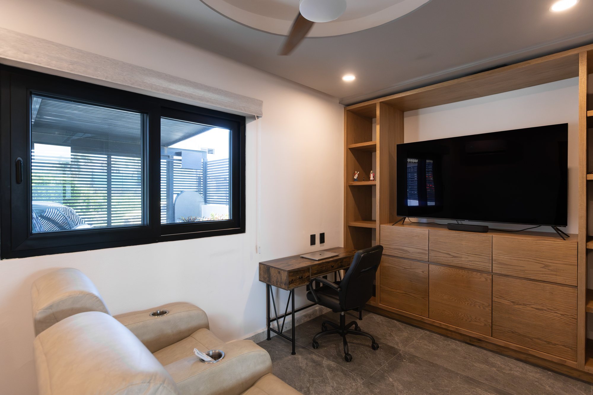 Ground floor room with recliners, a desk and a built-in media wall