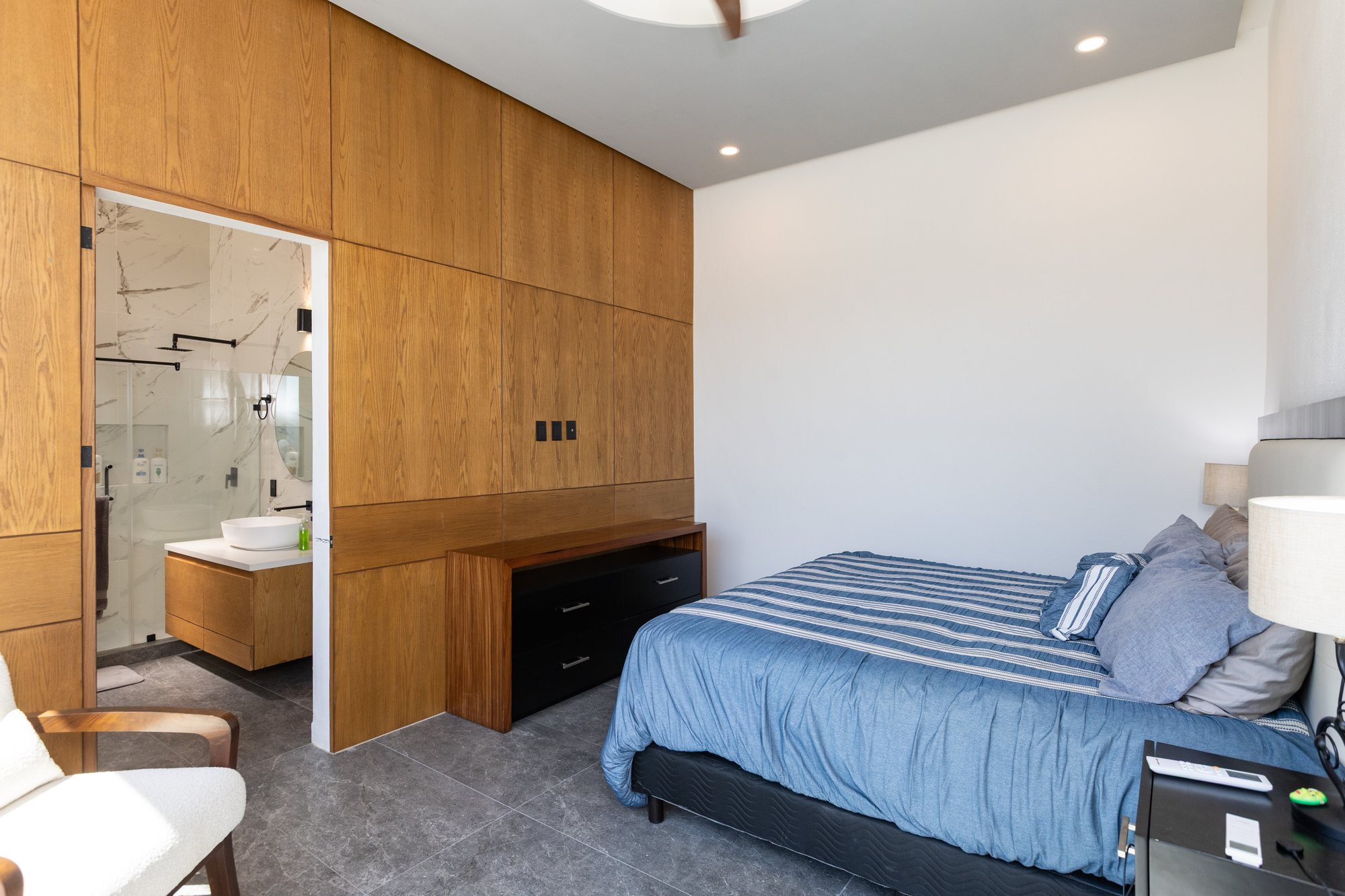 Primary bedroom with its bath beyond the wood-paneled wall