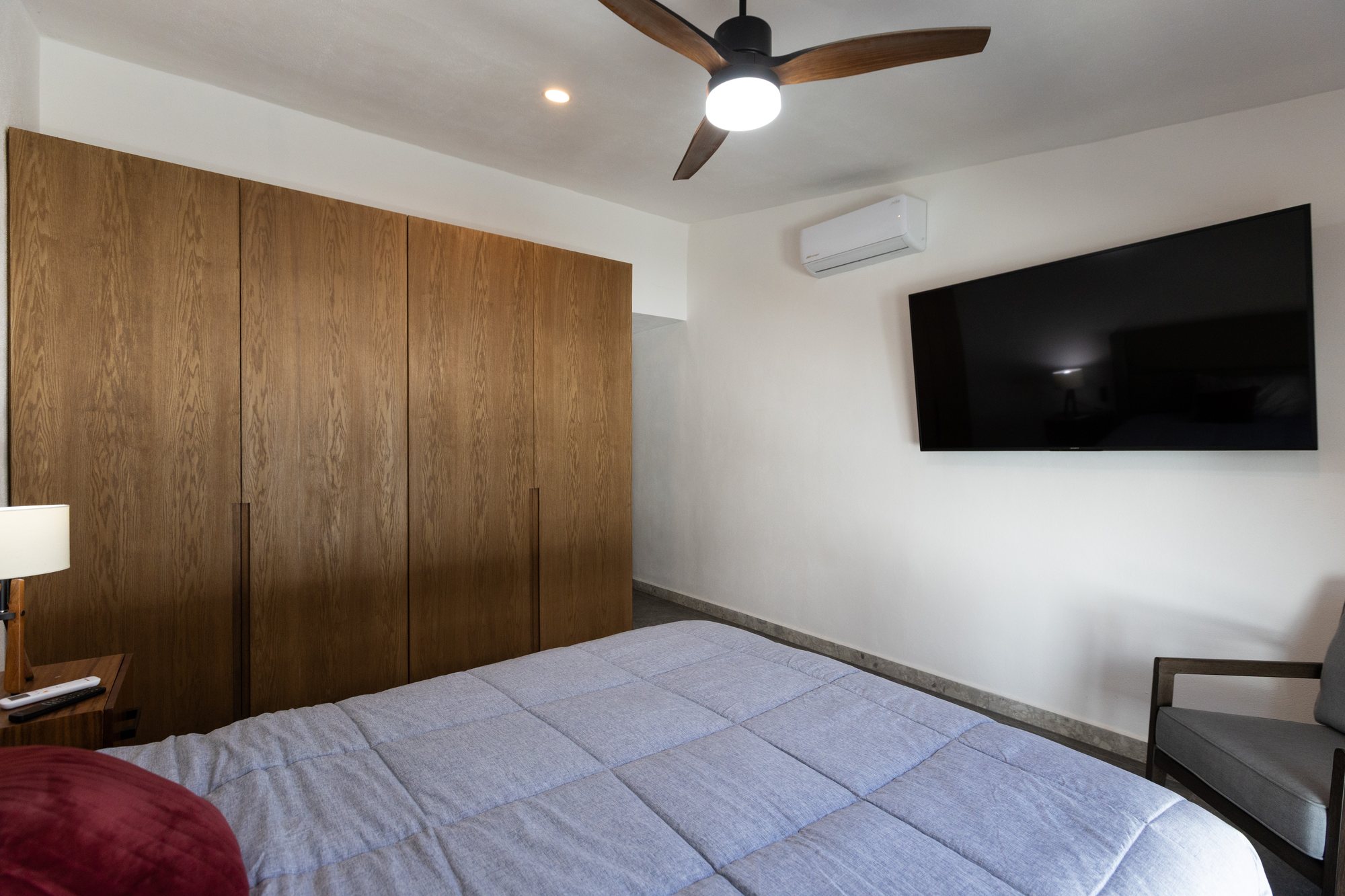 Bedroom with a wall of wood wardrobes and a wall-mounted TV