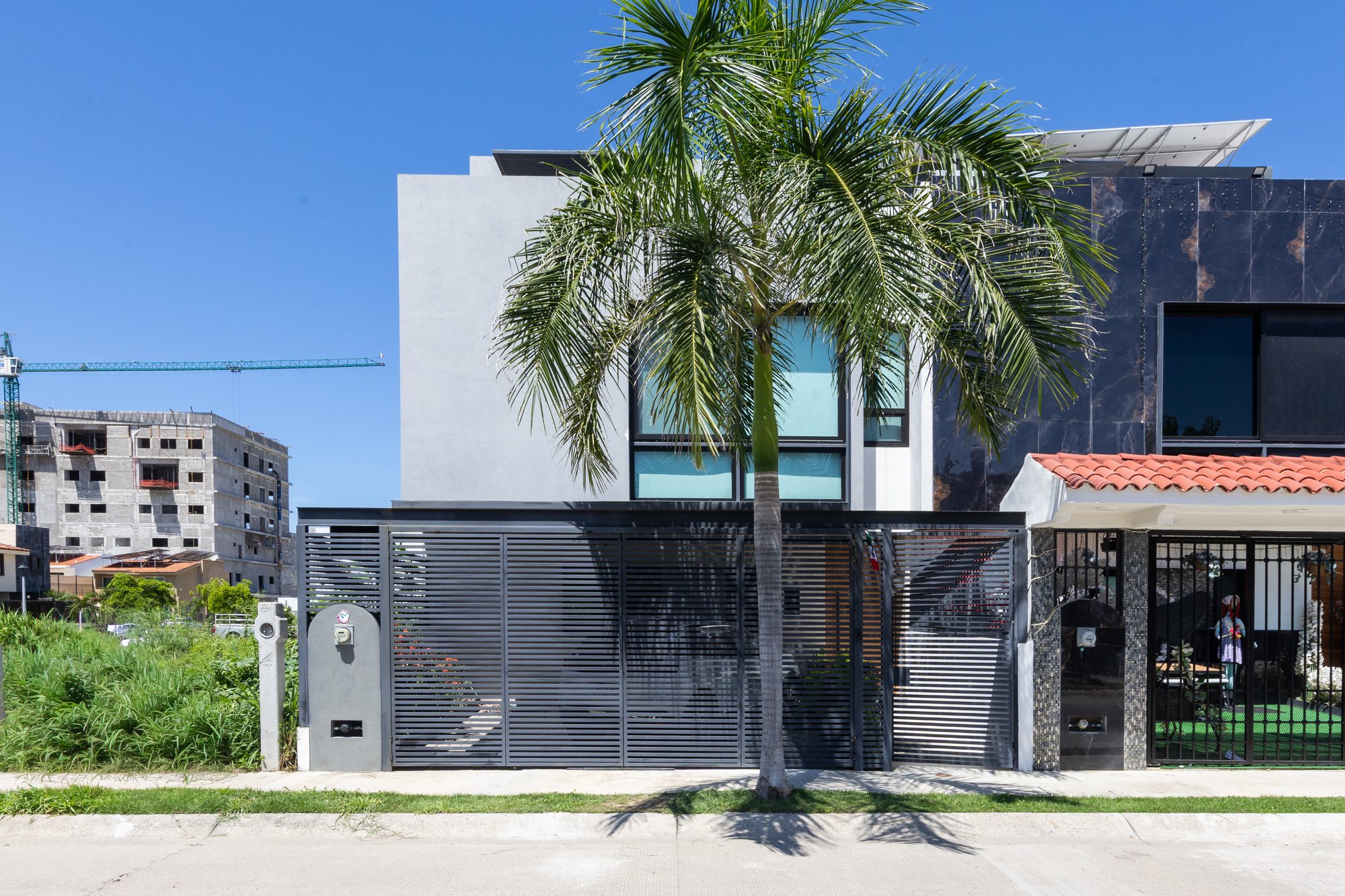 Two-story modern facade behind a louvered gate on Calle Lago Superior