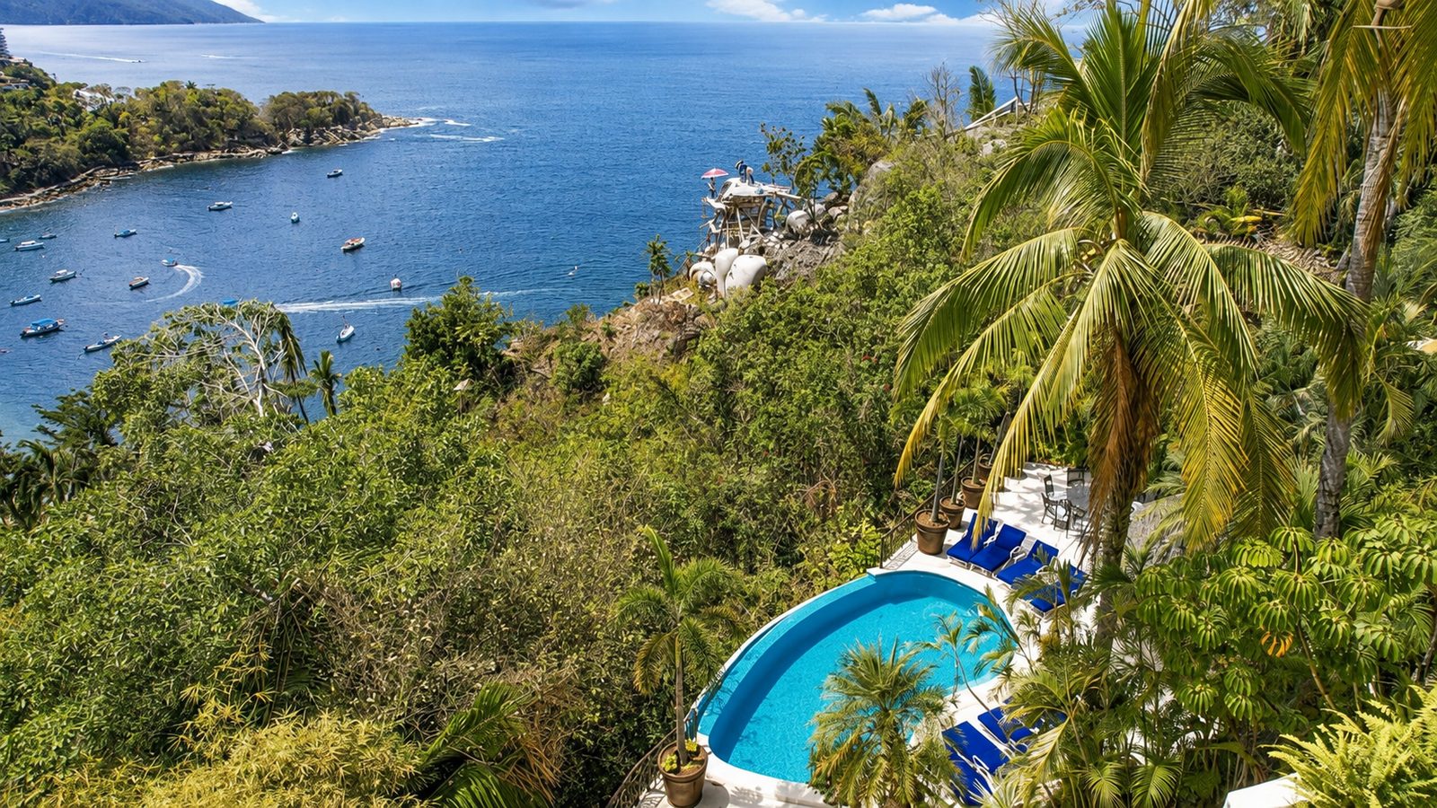 Pool and sun deck below the house with Mismaloya Bay and anchored boats