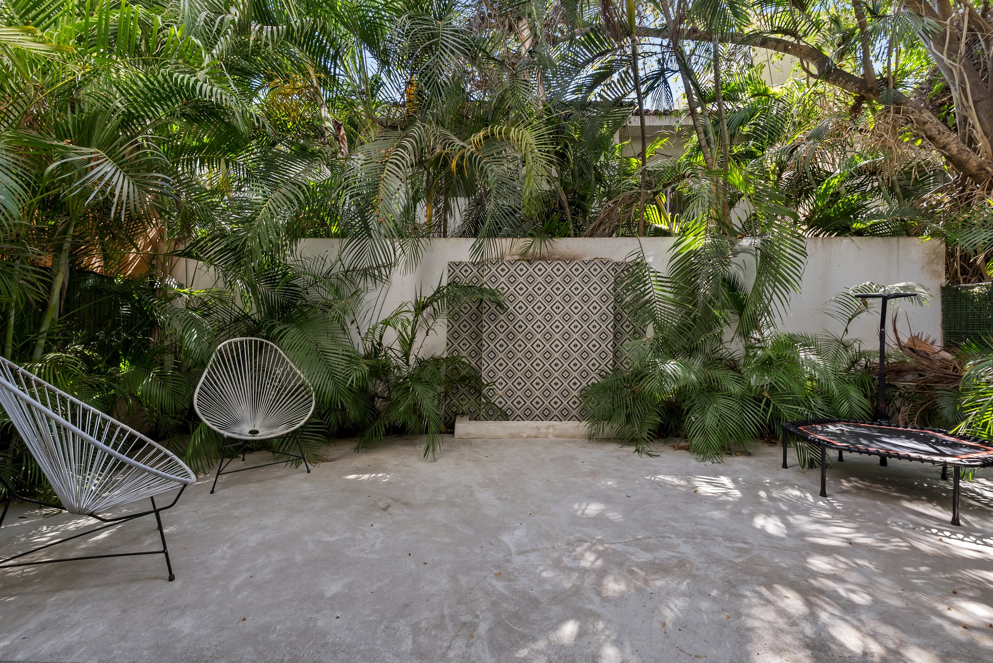 Patio jardín con muro de azulejo decorativo y palmeras