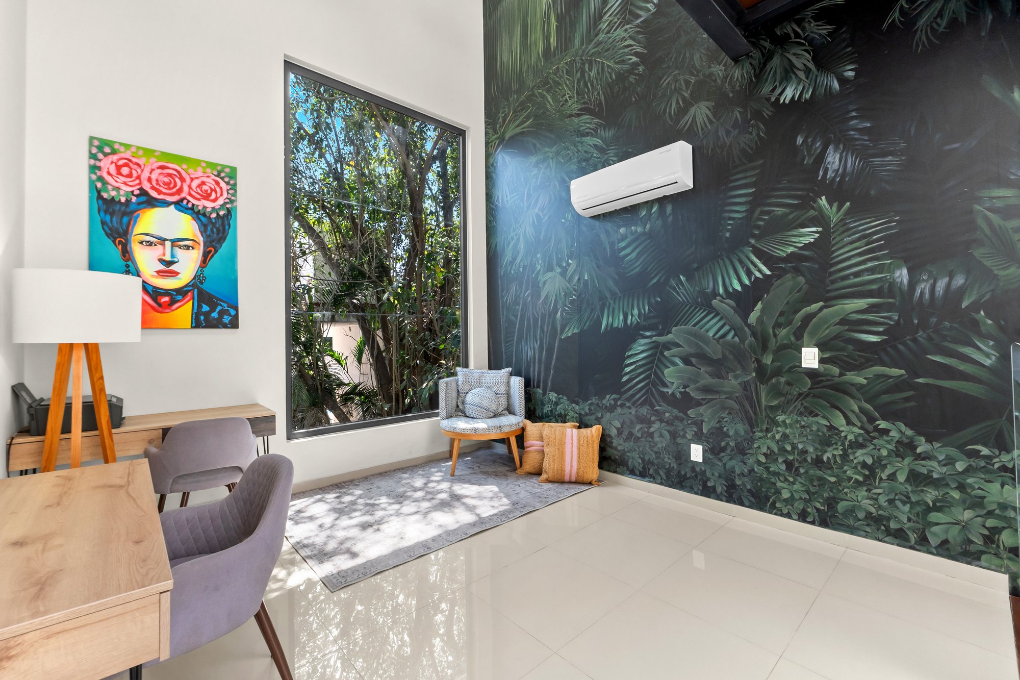 Estancia en planta alta con escritorio, arte colorido y ventana hacia los árboles