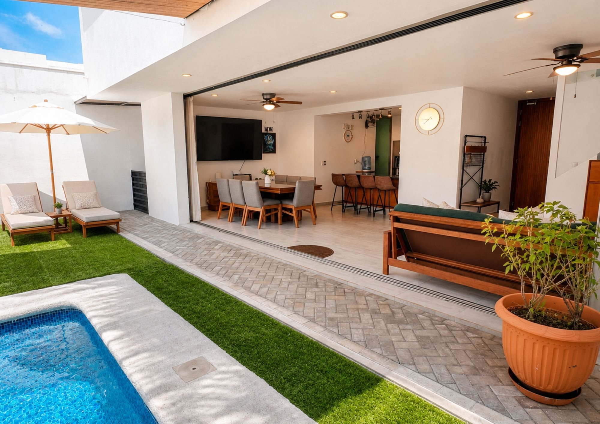 Sala y comedor abiertos directamente hacia la alberca y el jardín