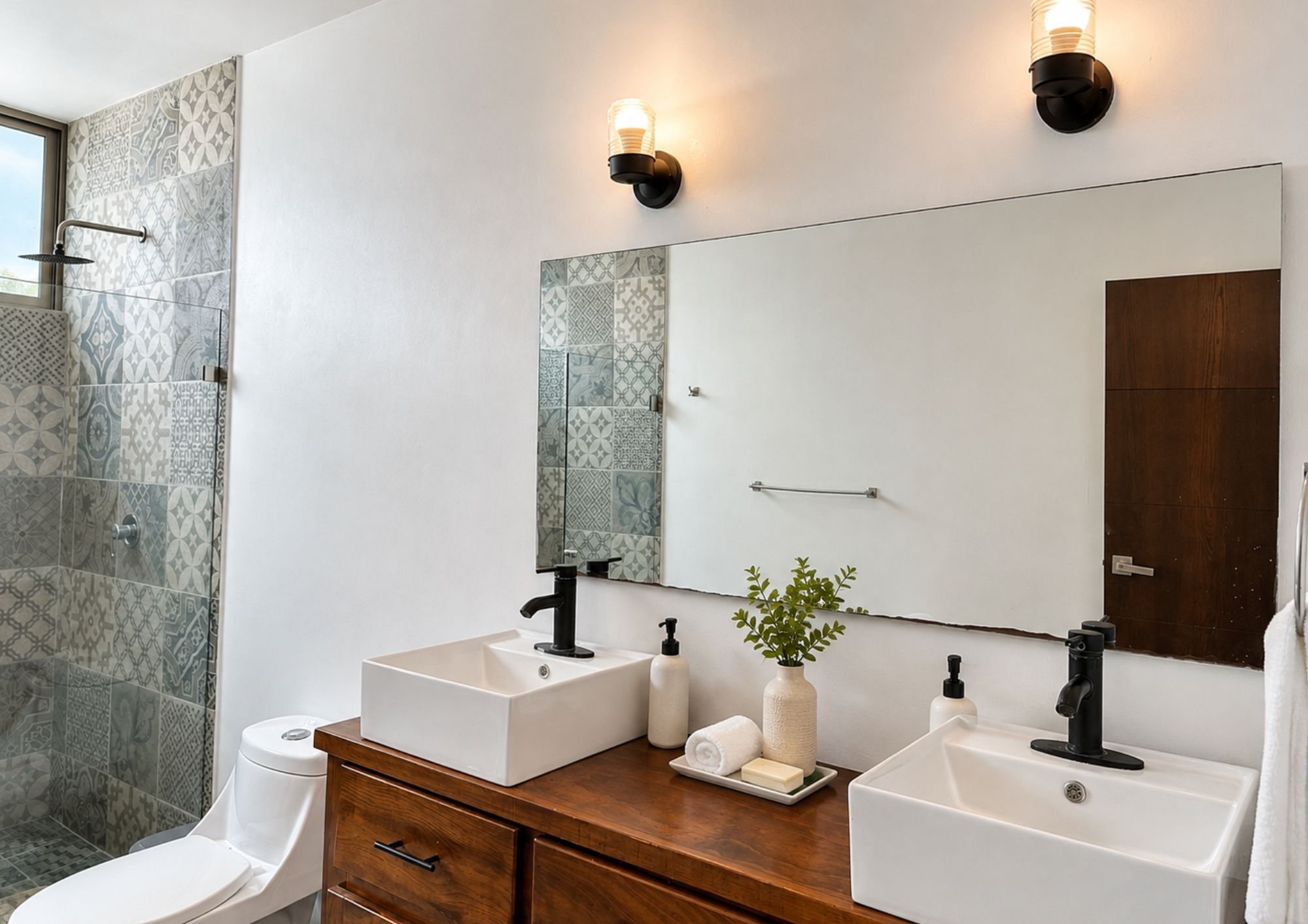 Baño con dos lavabos sobre cubierta, mueble de madera y regadera con azulejo