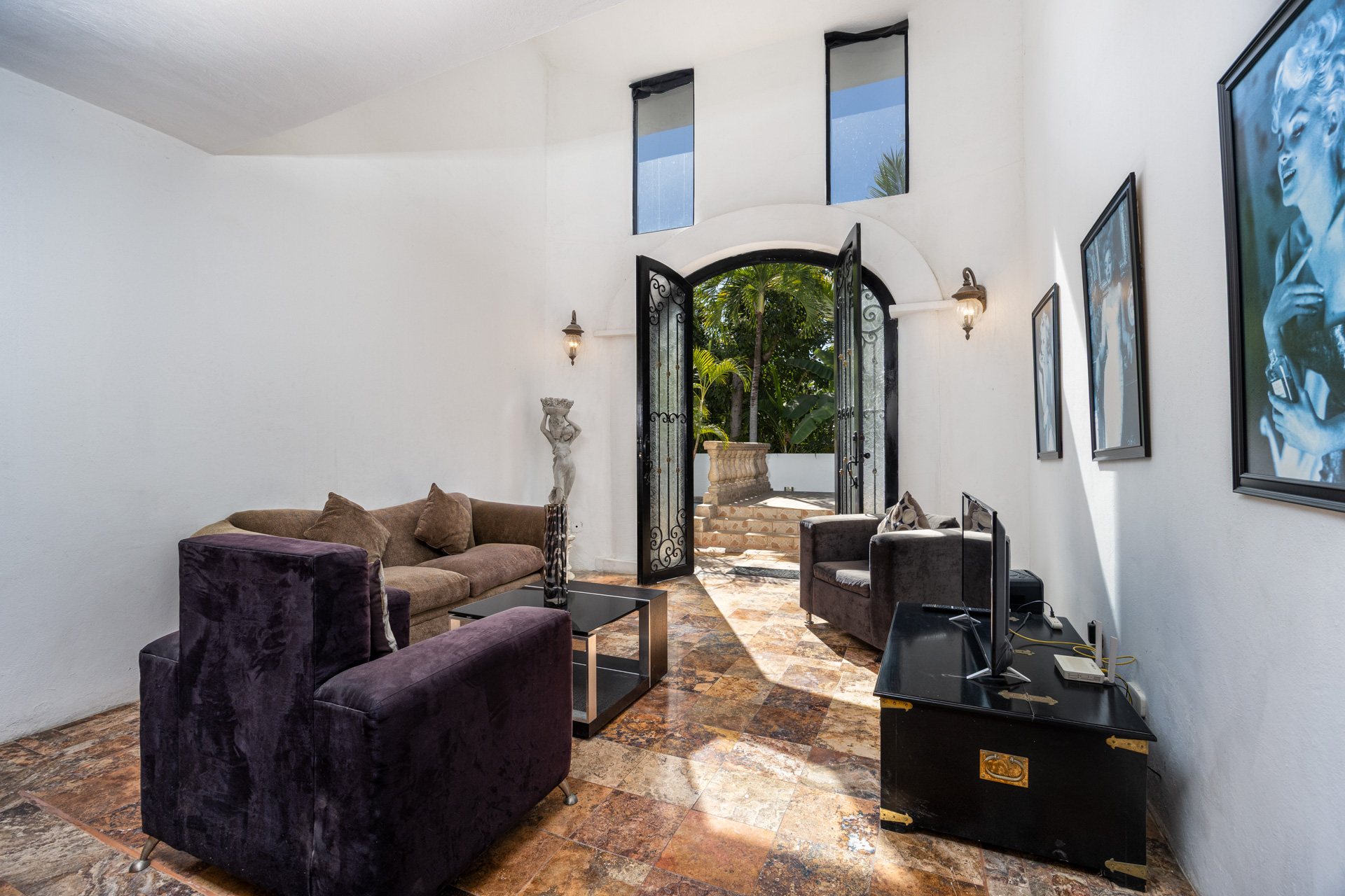 Sala de doble altura con puertas en arco hacia el jardín