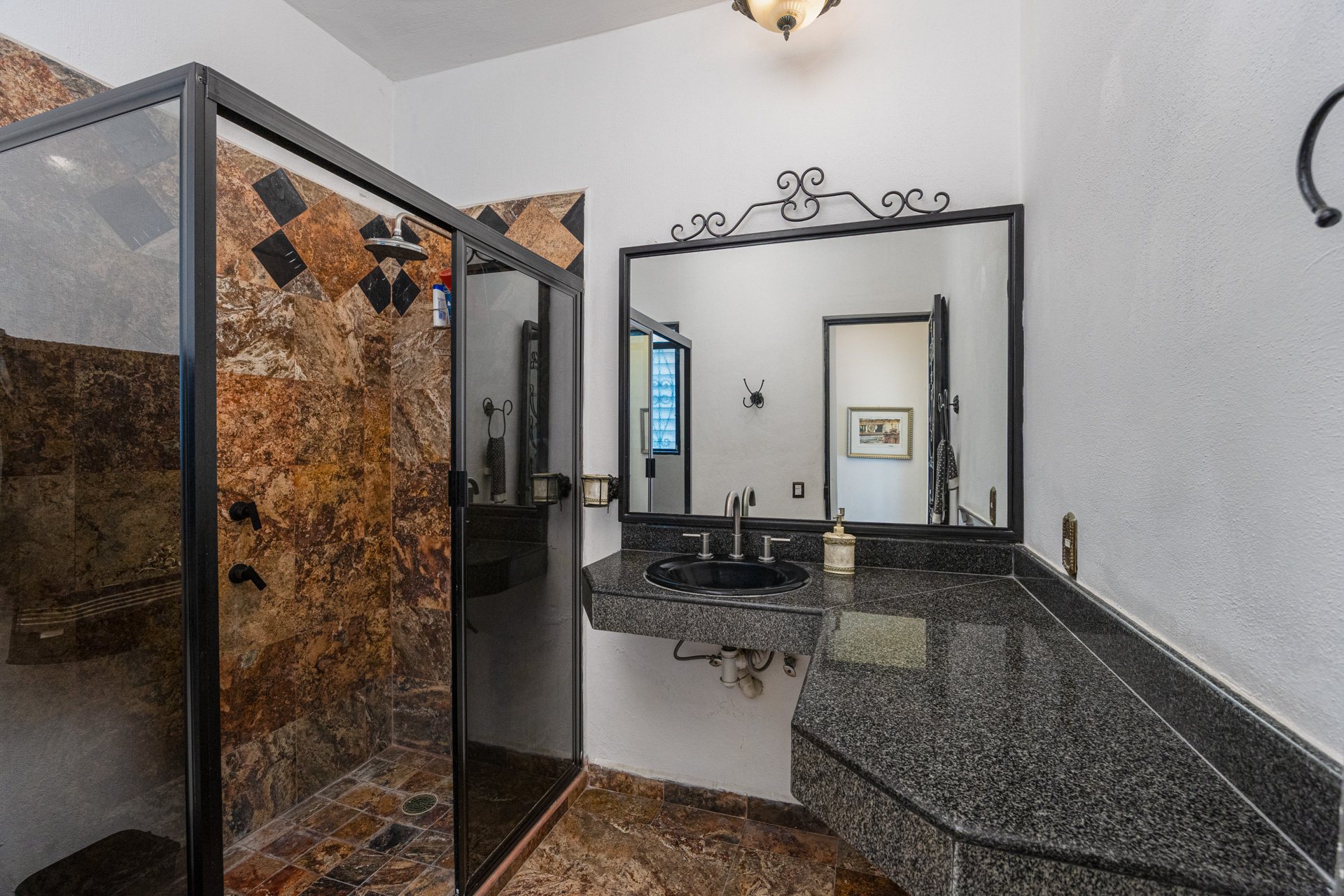 Baño con lavabo de granito y regadera de cristal