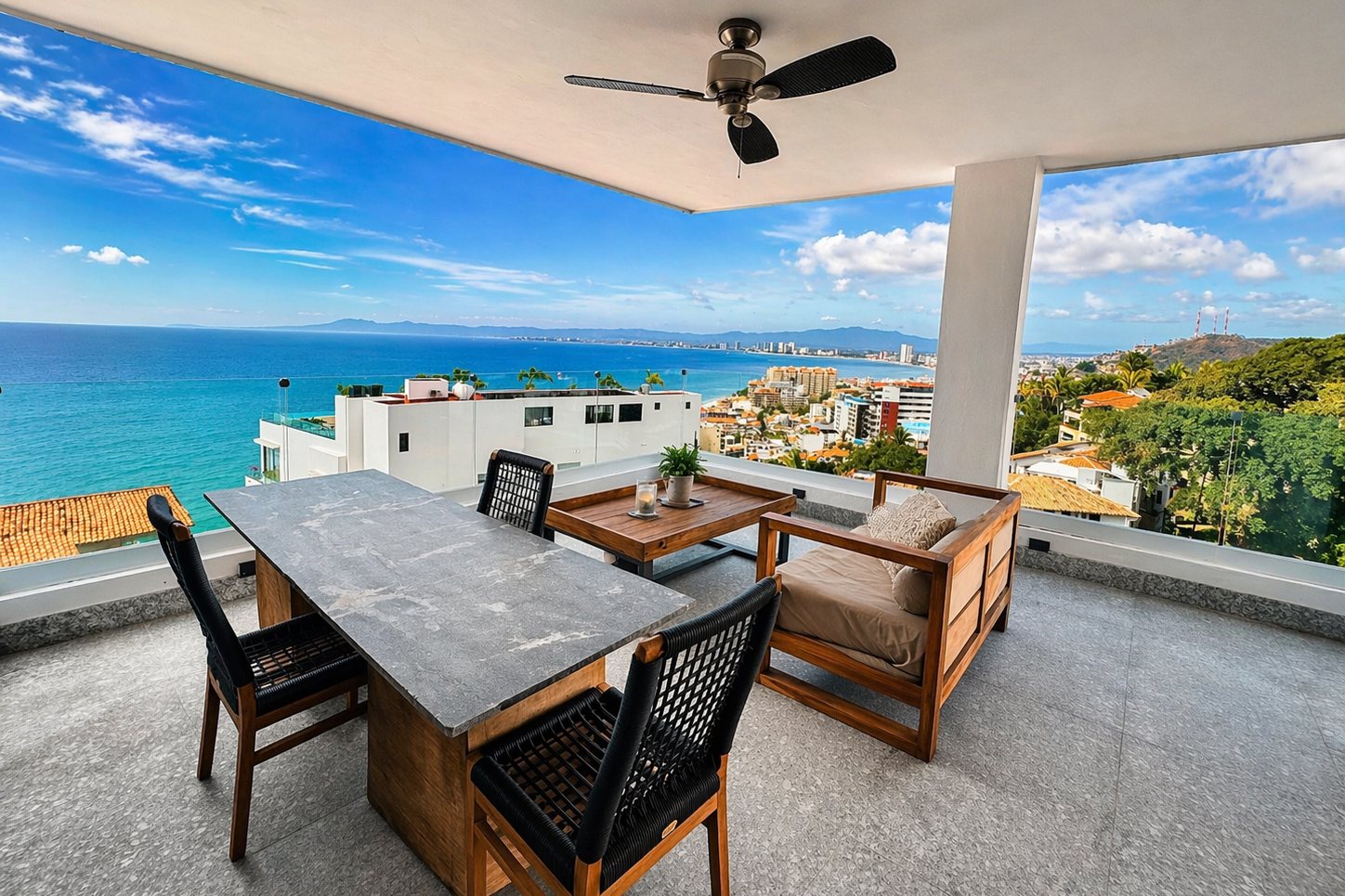Terraza techada con comedor y sillones, con vista a la bahía