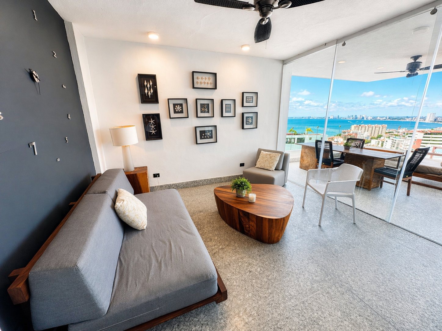 Sala con sofá cama de día, cuadros y puertas de cristal hacia la terraza